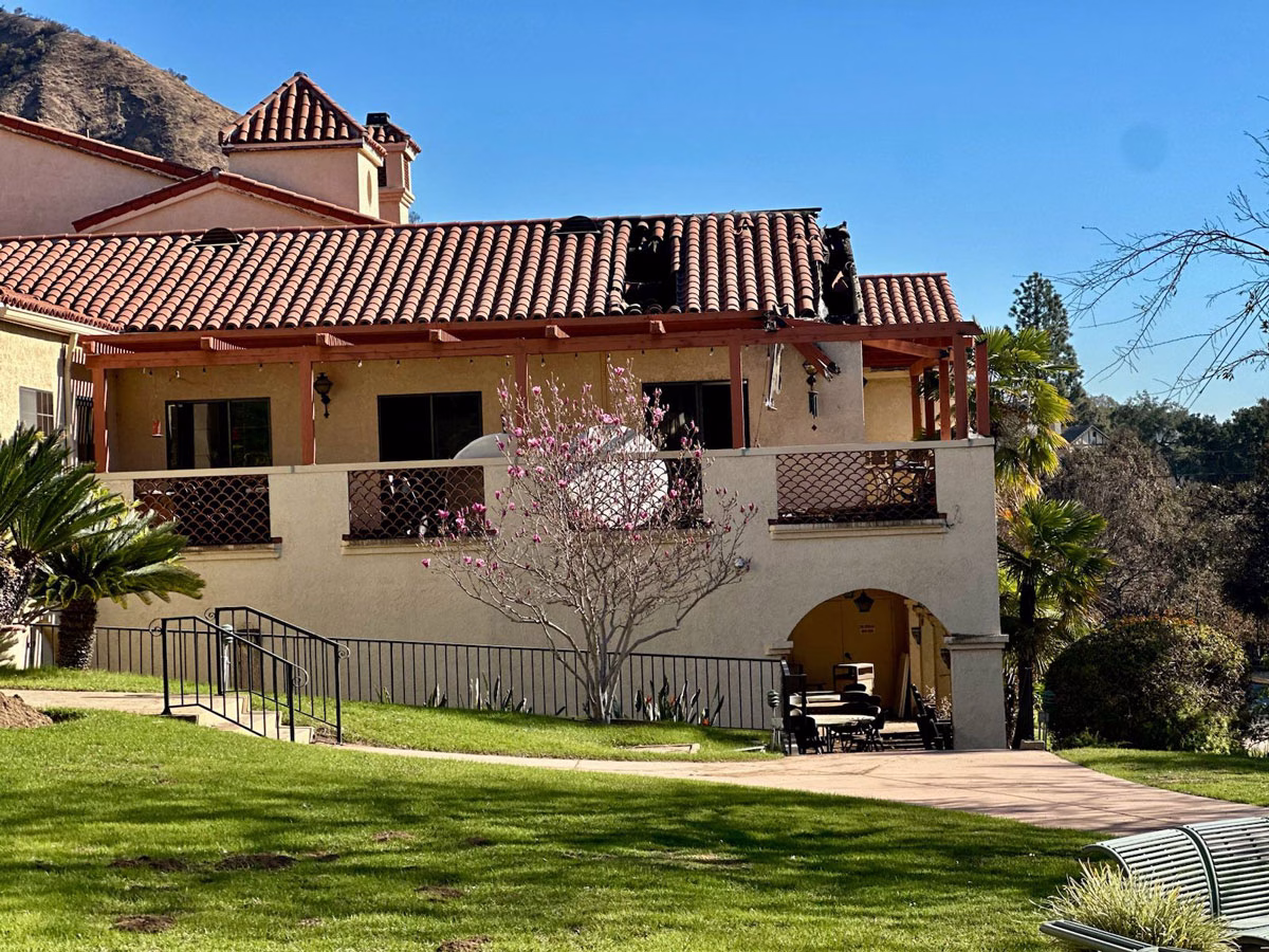 Retreat center building with visible roof damage after a fire, highlighting the need for restoration.