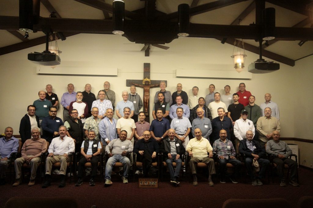 Participants gather for a men's retreat group photo beneath a crucifix in the conference hall at Mater Dolorosa Passionist Retreat Center.